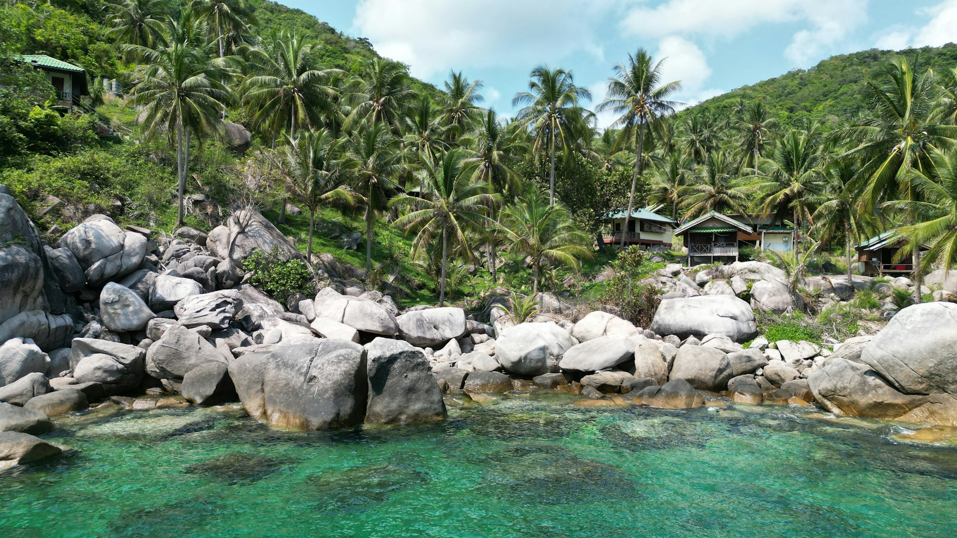 Koh Samui coastline in the dry season, with granite boulders, coconut palms and clear green water