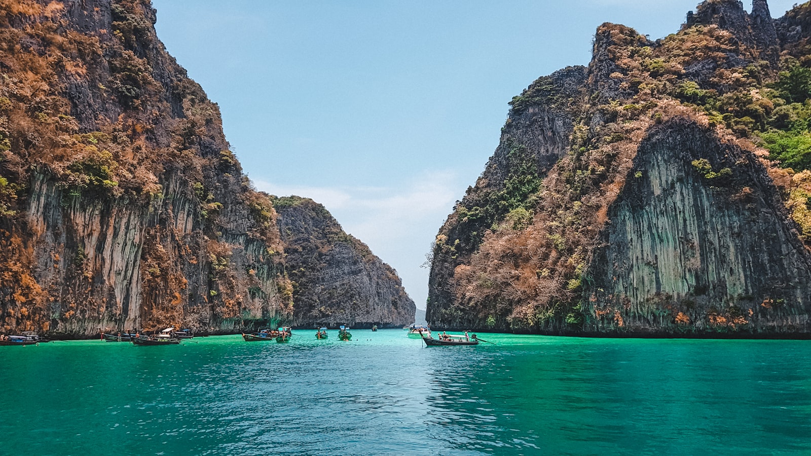 Boat at anchor beneath limestone rock formations in the Gulf of Thailand near Koh Samui