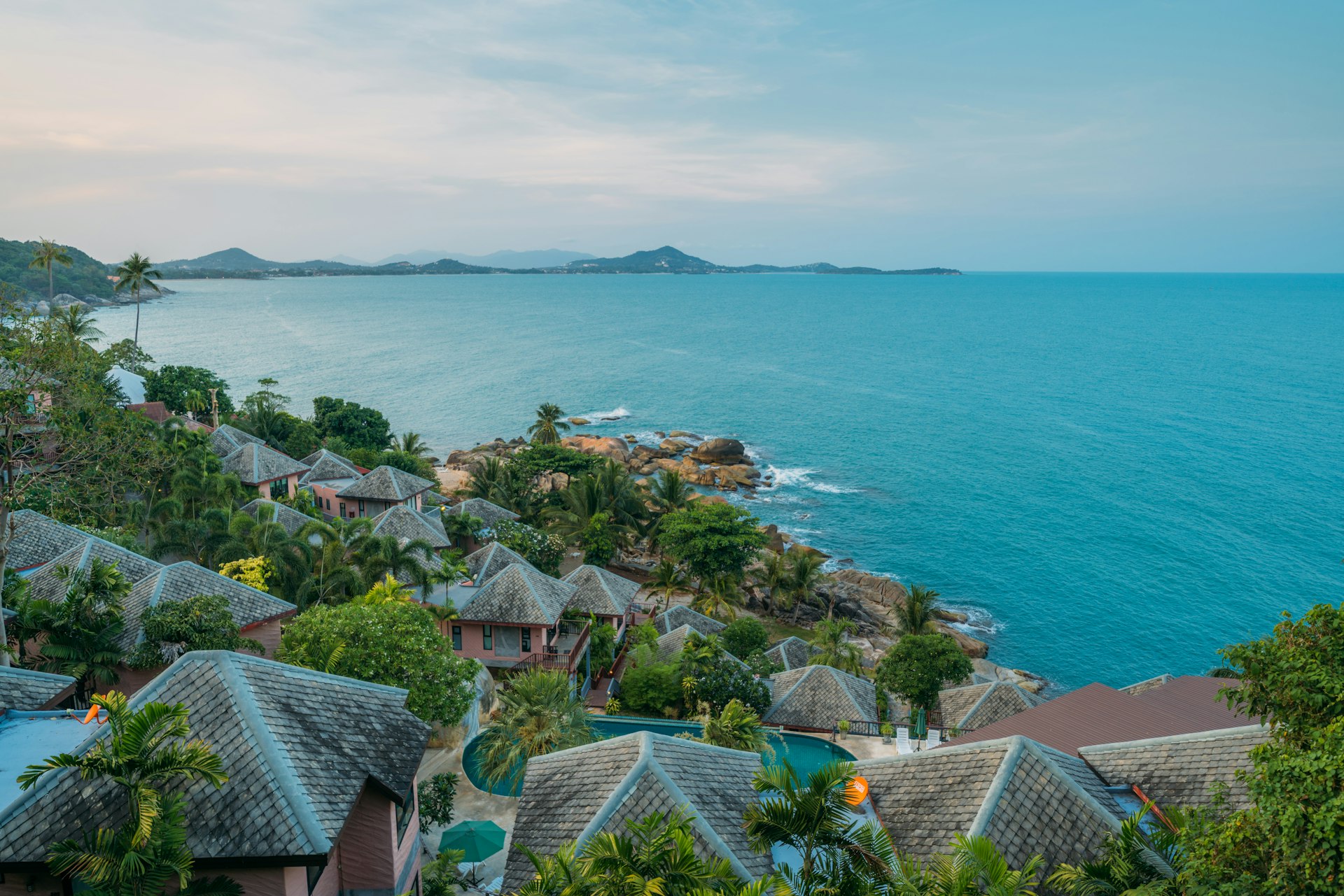 Aerial view of the Koh Samui coastline, with villas set among palms above turquoise water