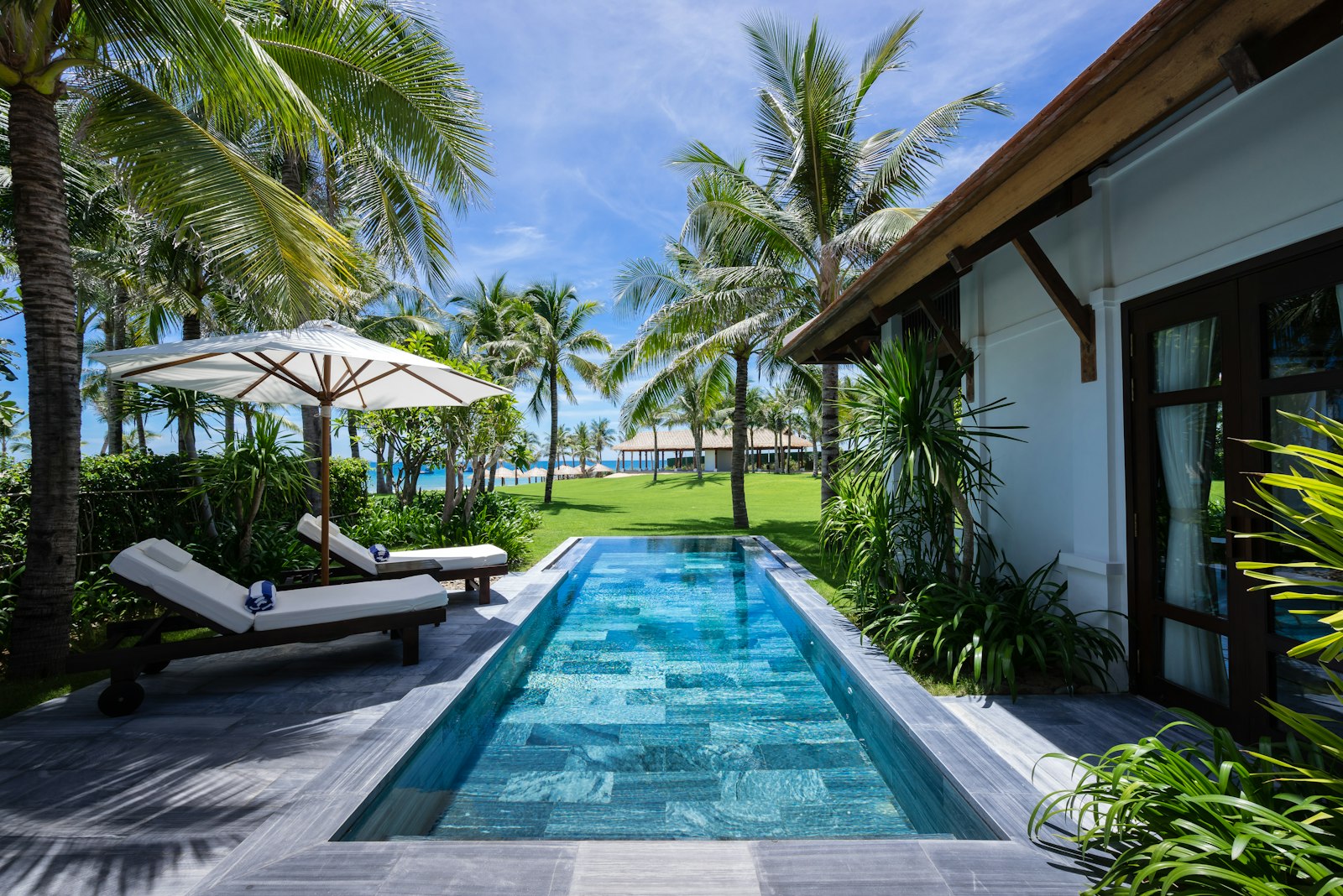 Private tropical pool villa with timber terraces opening onto the water