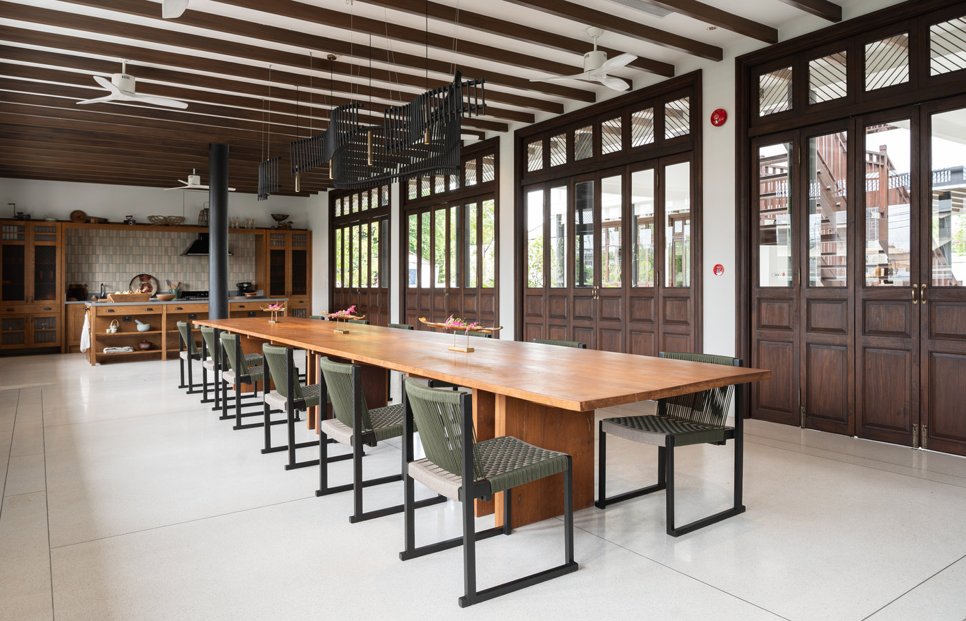 The long dining table at Siri Sala with dark timber doors and daylight
